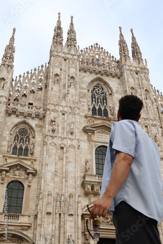 Boy gazing at Duomo di Milano on a cloudy day, photo from behind
