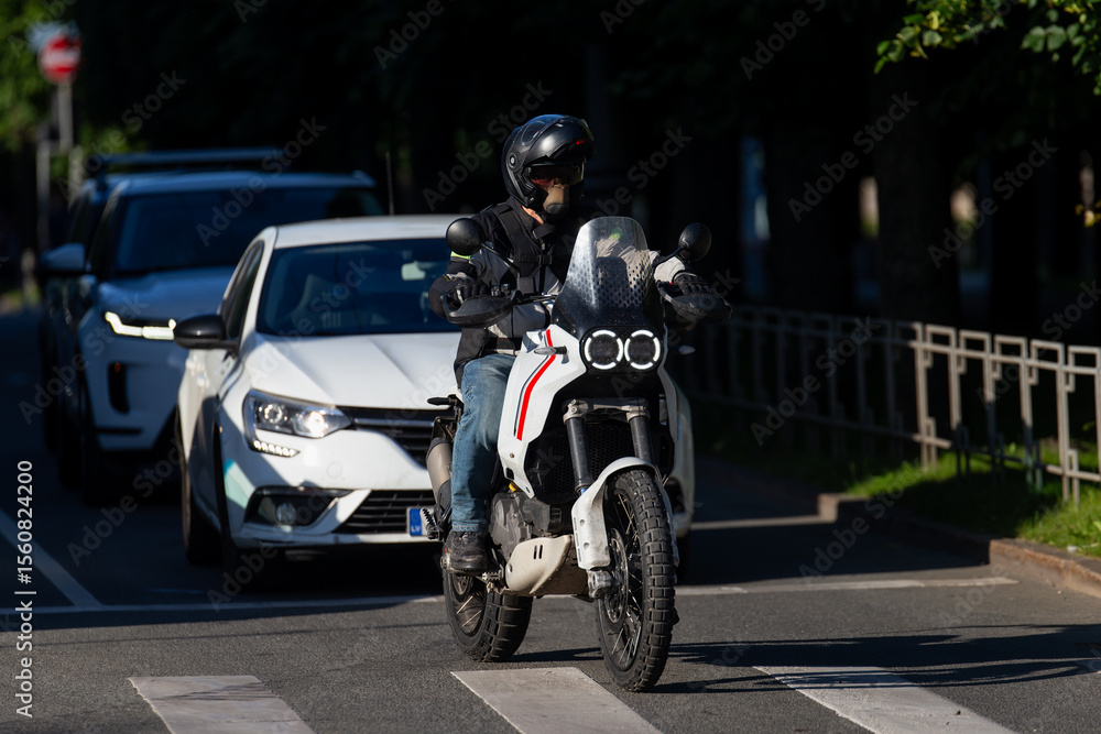 motorcyclist on white adventure bike waiting at pedestrian crossing in city traffic during sunny day with protective gear and helmet urban transportation safety commuting lifestyle road travel motorcyclist on white adventure bike waiting at pedestrian crossing in city traffic during sunny day with protective gear and helmet urban transportation safety commuting lifestyle road travel