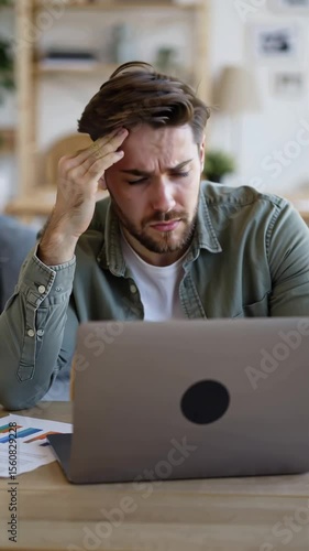 stressed male freelancer at table with laptop at home problems with project,