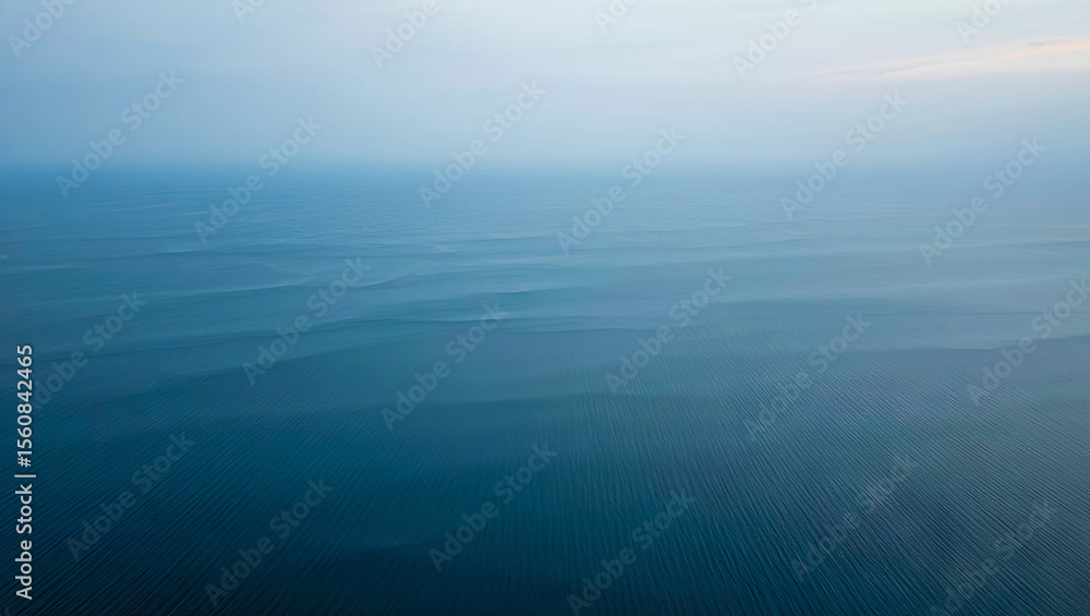 An expansive view of a tranquil ocean showcases soft, rolling waves under a pale blue sky during early morning hours, creating a peaceful atmosphere at sea An expansive view of a tranquil ocean showcases soft, rolling waves under a pale blue sky during early morning hours, creating a peaceful atmosphere at sea