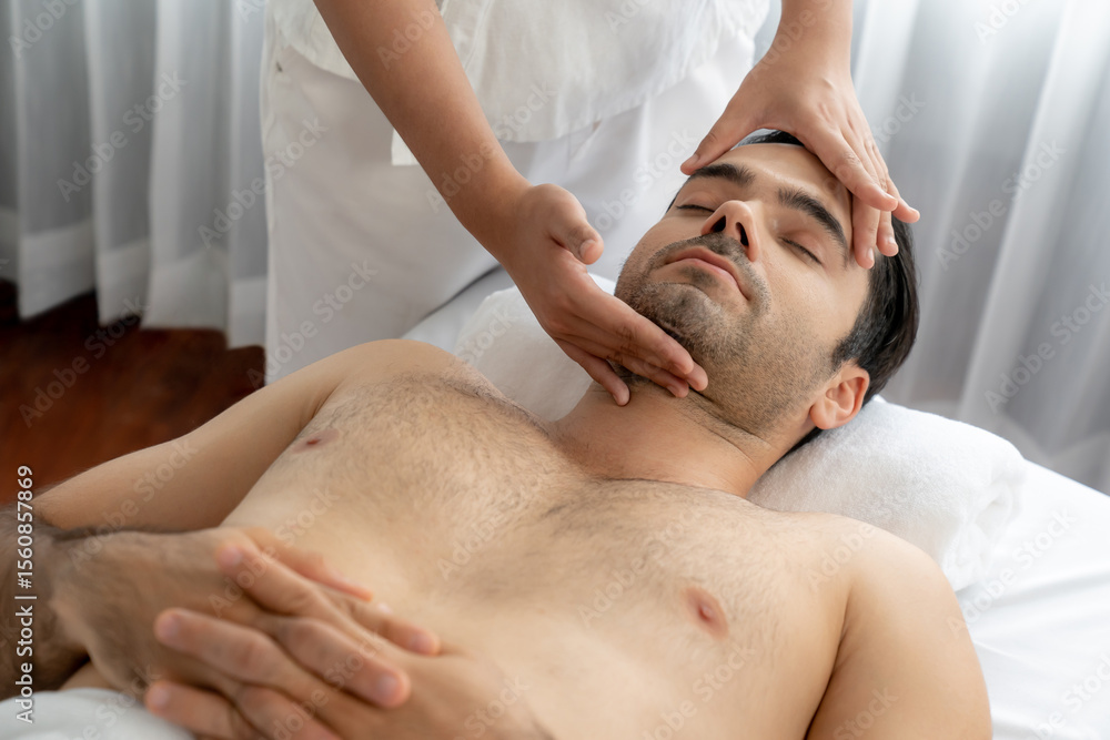 Caucasian man enjoying relaxing anti-stress head massage and pampering facial beauty skin recreation leisure in dayspa modern light ambient at luxury resort or hotel spa salon. Quiescent Caucasian man enjoying relaxing anti-stress head massage and pampering facial beauty skin recreation leisure in dayspa modern light ambient at luxury resort or hotel spa salon. Quiescent