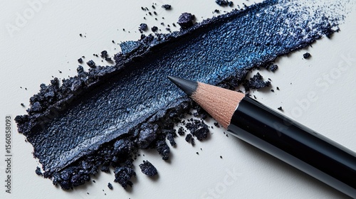 Dark blue eyeshadow and eyeliner pencil on a light background.