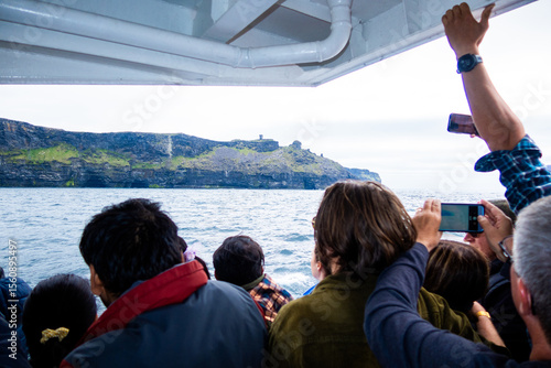 Tourists on a boat crowding to get pictures of the Cliffs of Mor near Galway on a Ferry Boat