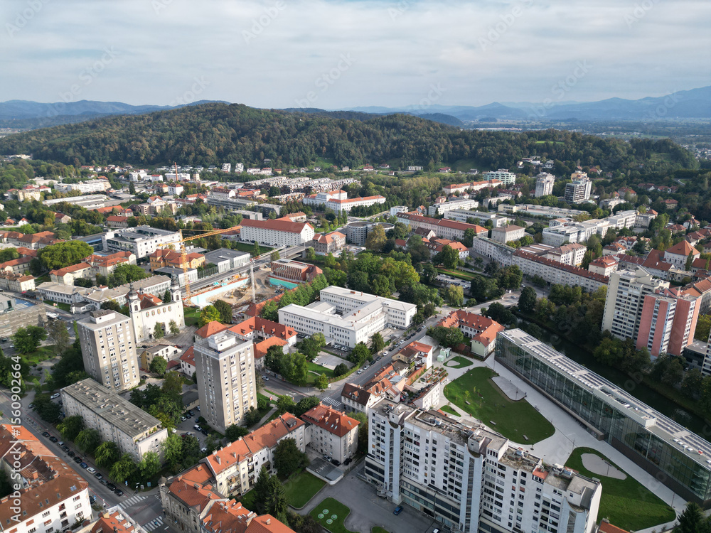 Obraz premium aerial view of ljubljana slovenia (european capital city in europe) castle on hill colorful roofs suburban neighborhood with mountains apartment buildings trees green nature hills river