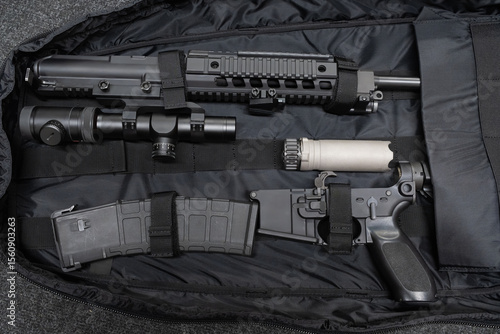 A disassembled modular rifle with accessories, such as an optical scope and a suppressor, neatly laid out in a tactical case for transportation.