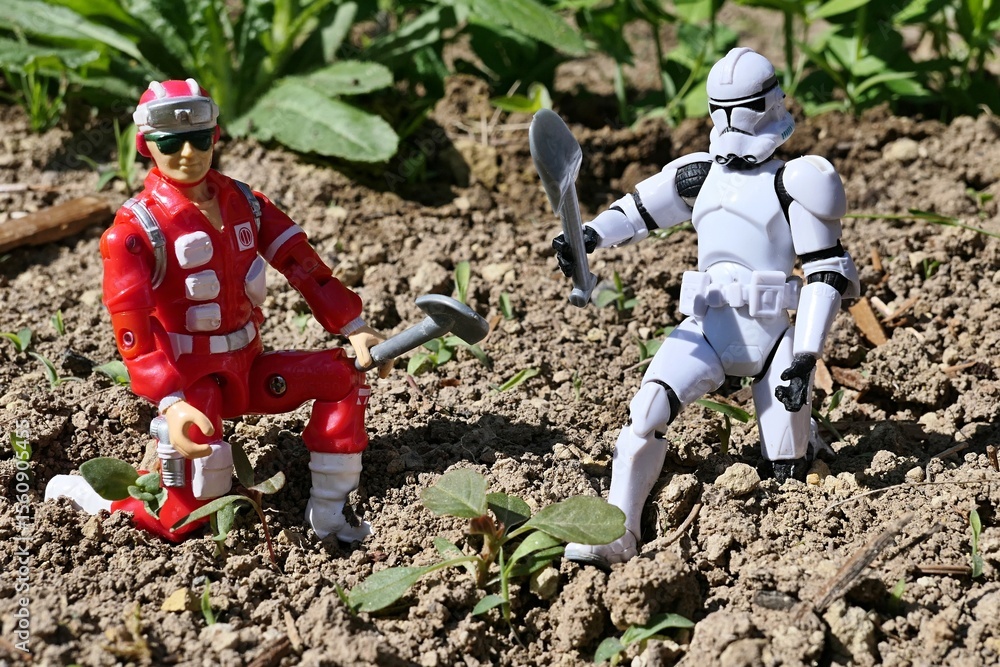 Naklejka premium GI JOE action figure of medic and rescue team member Lifeline cultivating garden with gray LEGO shovel together with figure of Star Wars clone trooper, sunlit by spring daylight sunshine. 