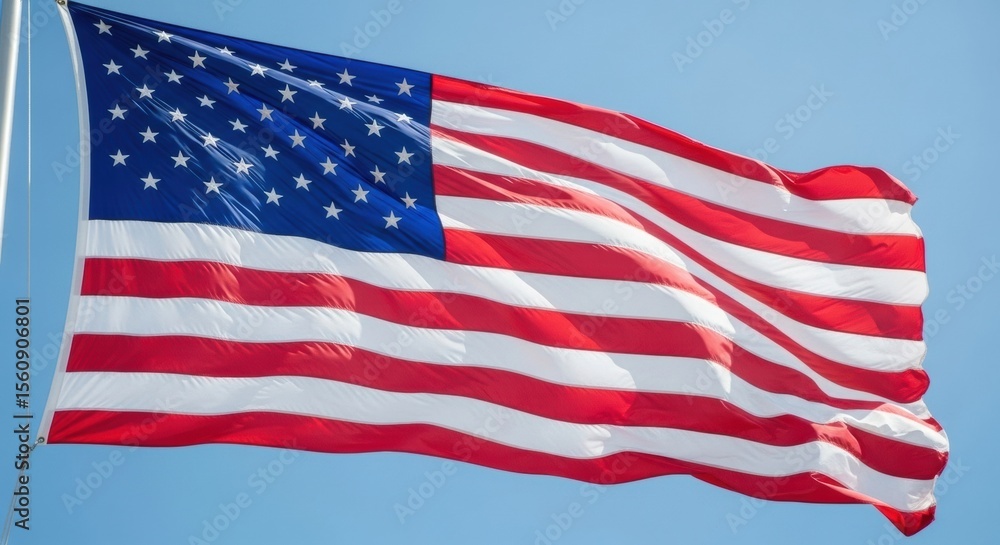 Obraz premium Large American Flag Billowing Against a Bright Blue Sky