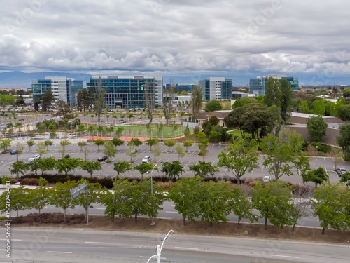Aerial view of Google's corporate headquarters in Mountain View, California, USA. The modern office buildings are surrounded by parking lots and green spaces.