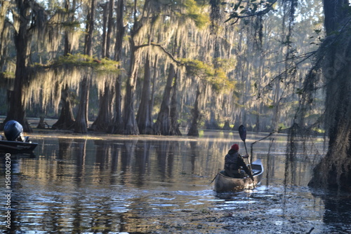 A man is kayaking on Caddo Lake in Texas at sunrise