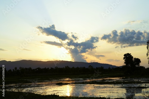 Sunrise or sunset paints a beautiful, calm landscape over the river or lake, with the sky reflecting orange and blue light on the water