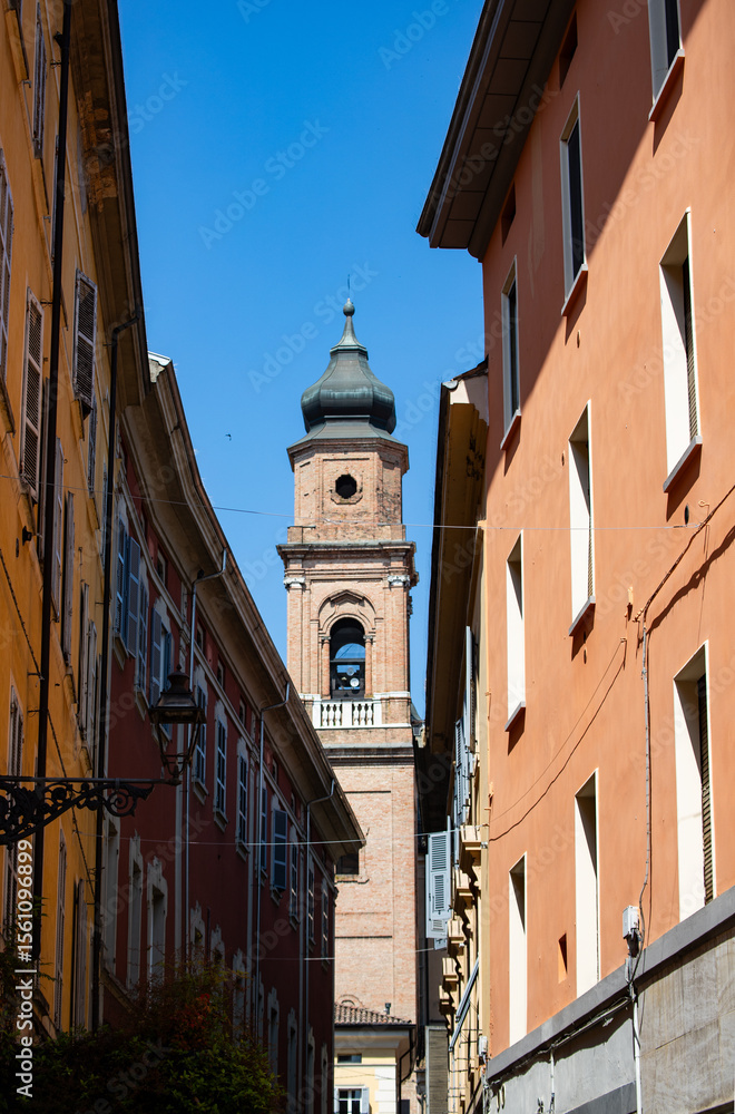 Fototapeta premium Historic city alley leading to an ancient bell tower sunny day scenic view.