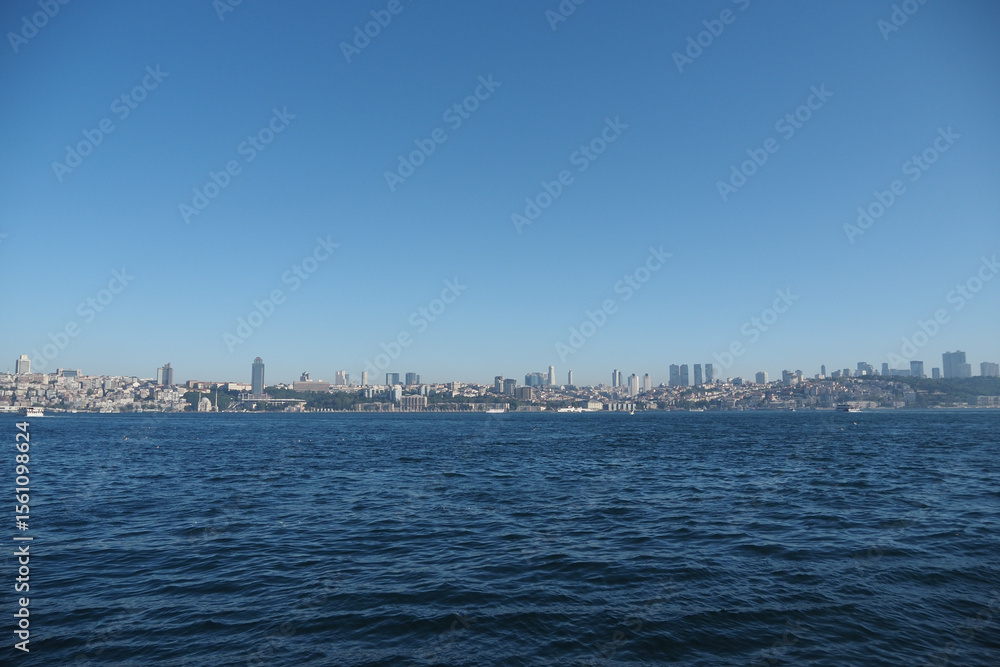 View of city skyline by the calm sea during daytime View of city skyline by the calm sea during daytime