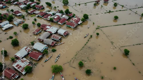 Extensive Brown Water Flood Devastating Village Houses Submerged in Rural Area with Transport Boats And Varied Roofs Aerial View