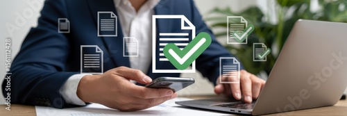 Businessperson reviewing documents on a laptop and mobile phone.