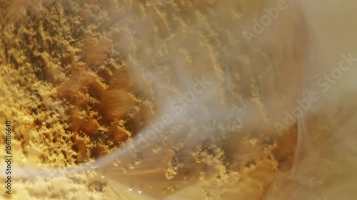 Vertical video. Ink spread. Watercolor fume. Dissolving powder orange swirl color defocused round diamond water abstract texture background.