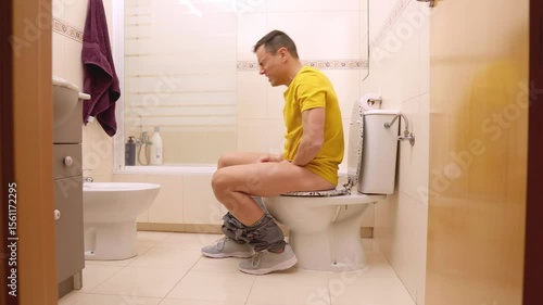 Man suffering from stomach ache sitting on toilet