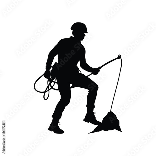 Silhouette of climber with helmet using rope to scale rock surface