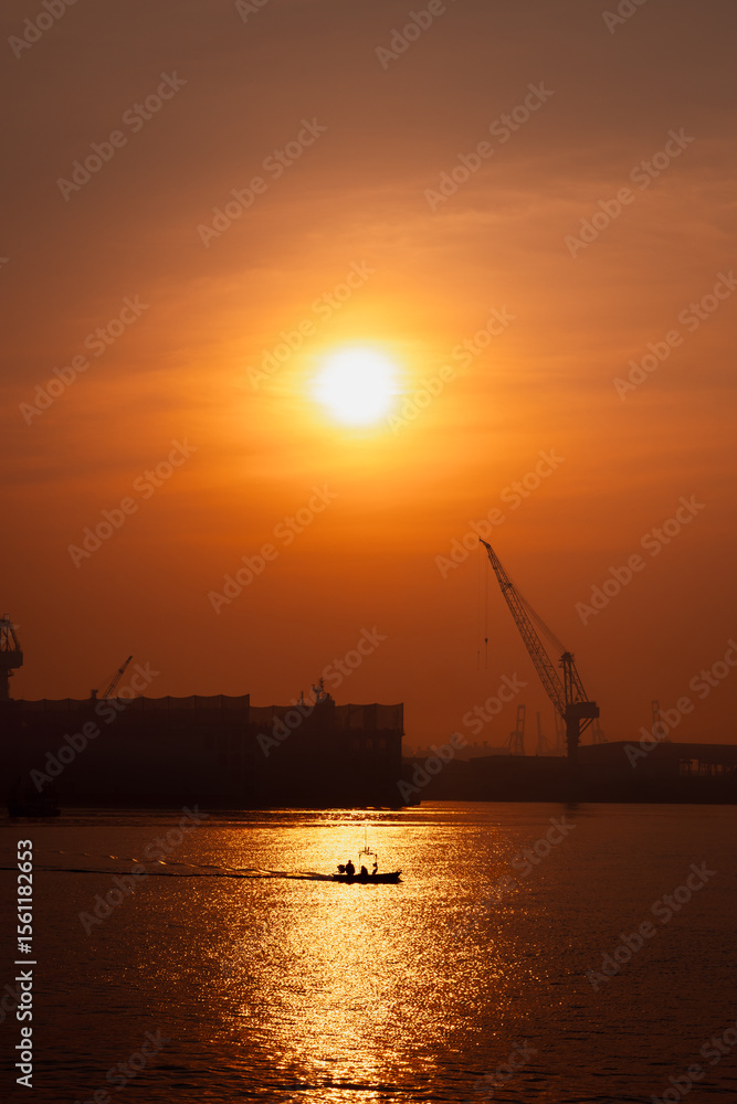 morning scene golden hour of the sun is rising, silhouette of shipyard working or mantainance and repair by crane, silhouette of fishing boat full speed i sea. morning scene golden hour of the sun is rising, silhouette of shipyard working or mantainance and repair by crane, silhouette of fishing boat full speed i sea.