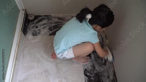 Cheerful daughter cleaning the bathroom,Child or girl brushing the bathroom floor clean to kill bacteria or dirty disease and disinfect dust 