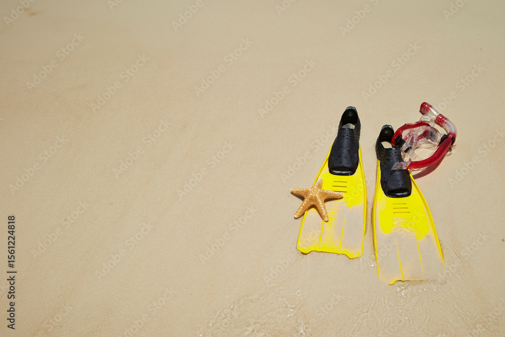 Obraz premium Yellow flippers, snorkel set and starfish on the beach