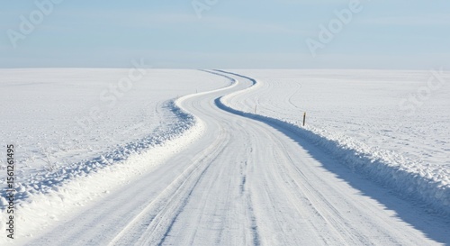 Serpentine road cuts a snowy path through a vast winter landscape under a crisp sky