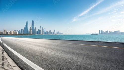 Modern city skyline across the turquoise ocean with a scenic coastal road in the foreground