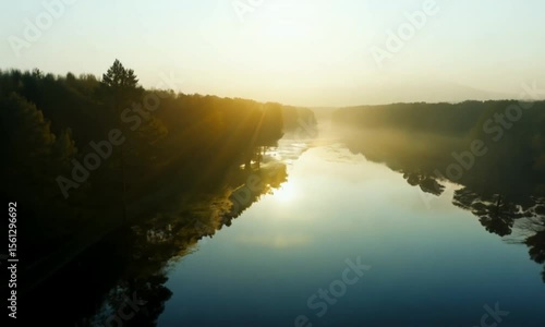 Wallpaper Mural Generate a tranquil drone sequence flying low over a calm river at dawn, where early mist clings to the surface and surrounding trees reflect perfectly in the water. Highlight balance, stillness, and  Torontodigital.ca