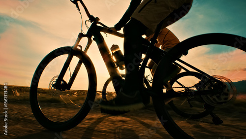 A close-up shot of a person riding a bicycle on a dirt road at sunset, emphasizing the freedom and thrill of off-road cycling.