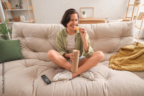 Young woman sitting on sofa...