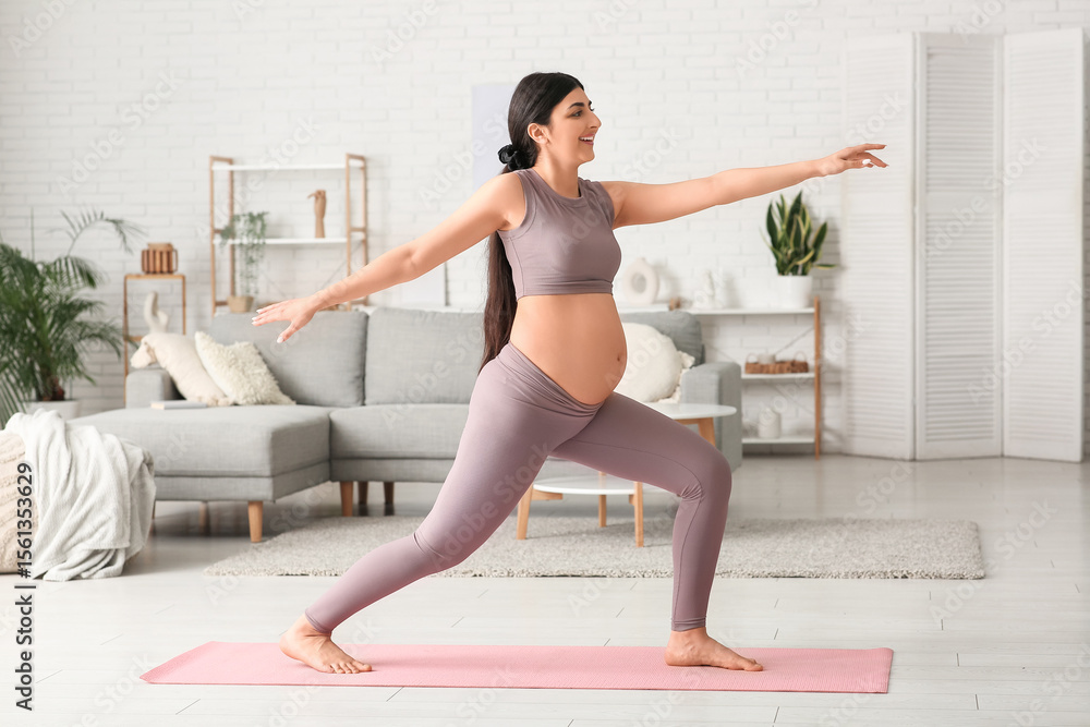 Fototapeta premium Beautiful pregnant woman doing yoga exercise at home
