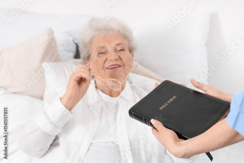 Caregiver giving Bible to s...