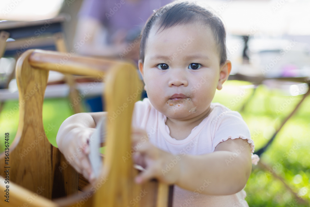 Fototapeta premium Baby is enjoying leisure time outdoors with family during picnic, surrounded by people and nature, capturing concept of joyful moments and togetherness in natural setting
