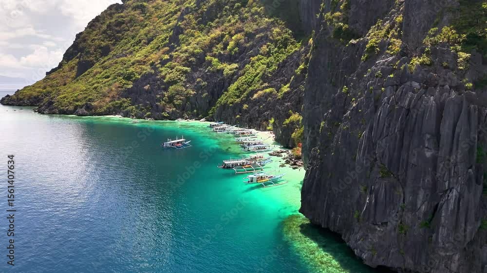 Traditional outrigger boats float on turquoise waters near limestone cliffs and lush forest at Talisay Beach on Tapiutan Island, Philippines, offering a serene tropical seascape and coastal beauty Traditional outrigger boats float on turquoise waters near limestone cliffs and lush forest at Talisay Beach on Tapiutan Island, Philippines, offering a serene tropical seascape and coastal beauty