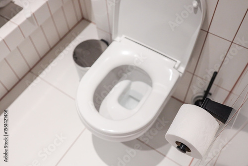 фотографія Top-view modern hotel WC with pristine ceramic bowl, open lid, wall-mounted tiss