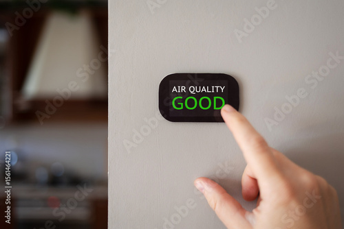home air quality index monitor on wall shows good green good