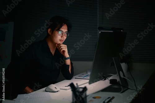 Foto Focused businessman staying late to complete important projects,in a dimly lit office