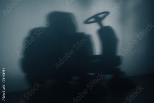 Wallpaper Mural Shadow of a cleaning vehicle with prominent steering wheel cast on a wall in dim lighting, abstract industrial silhouette Torontodigital.ca