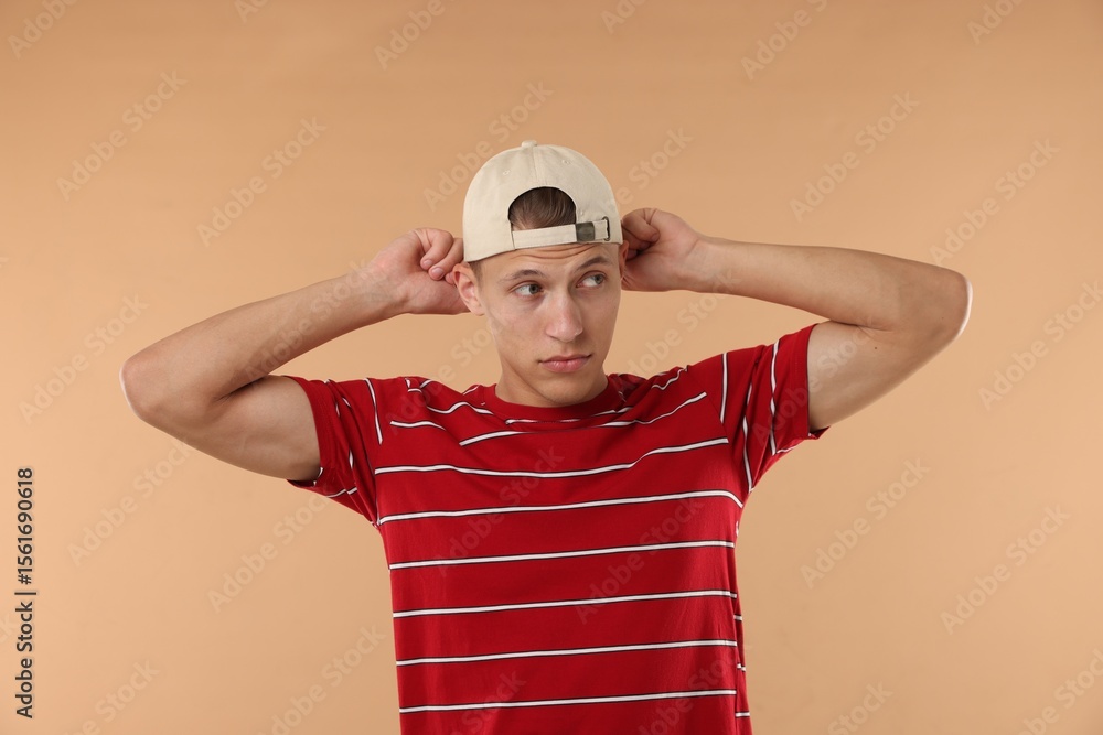 Naklejka premium Young man in stylish baseball hat on beige background