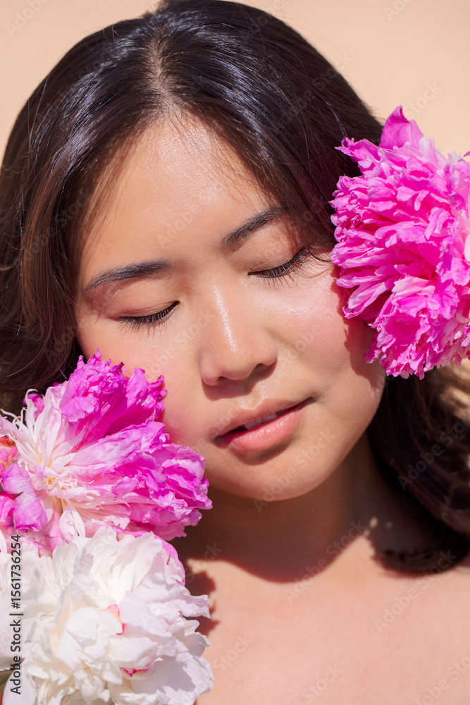 Fototapeta premium Asian woman with closed eyes, surrounded by vibrant pink and white flowers, embodies tranquility and beauty, showcasing a serene moment in nature with floral elements