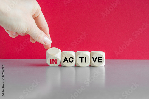 Active or inactive symbol. Businessman turns wooden cubes and changes the word Inactive to Active. Beautiful grey table red background. Business and active or inactive concept.