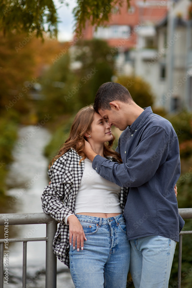 Fototapeta premium Young Cute Female Hugs Boyfriend. In Autumn Outdoor. Lovers Walking in Park. Attractive Funny Couple. Lovestory in Forest. Man and Woman. Cute Lovers in the Park. Family Concept. Happy Couple.
