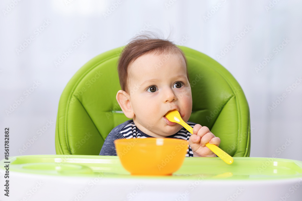 Cute little baby eating on feeding chair at home Cute little baby eating on feeding chair at home