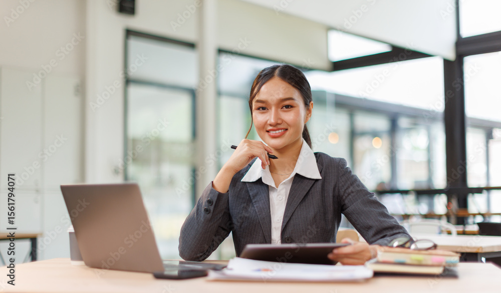 Fototapeta premium Young asian business woman sitting at the office and using laptops for document work. Confident professional female wearing business casual 
