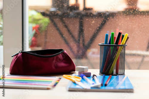 School supplies on a table. Pencils, markers, a ruler, erasers, a notebook, a pen, erasers, and a sharpie. Everything ready for back-to-school.