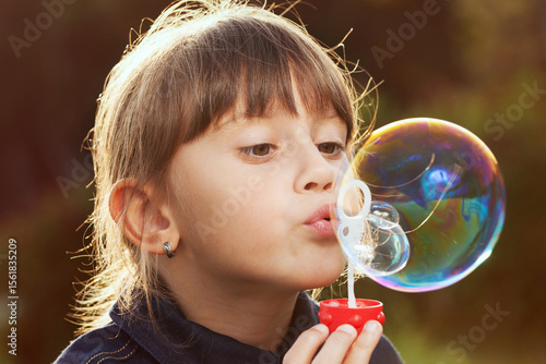 Little girl inflates a big bubble.