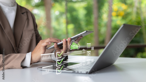 Fotografía Businesswoman using tablet and laptop with carbon credit icons and green checklists, representing eco-friendly digital business and ESG compliance