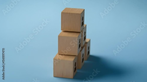 Six light brown wooden cubes, each with a person cutout, are stacked in a pyramid shape on a light blue surface.