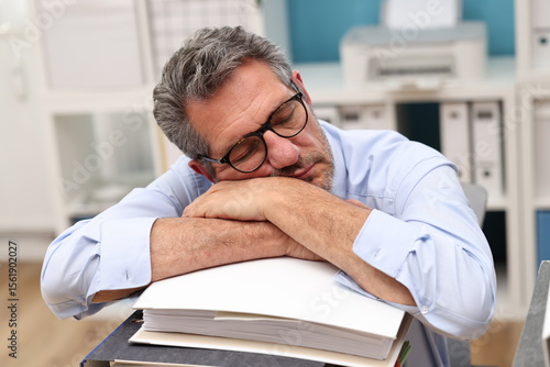 Office worker with glasses sleeps on a pile of files