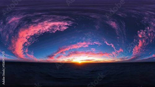 A beautiful sunset over the ocean. The sky is a deep blue with pink and orange clouds. The sun is setting in the distance