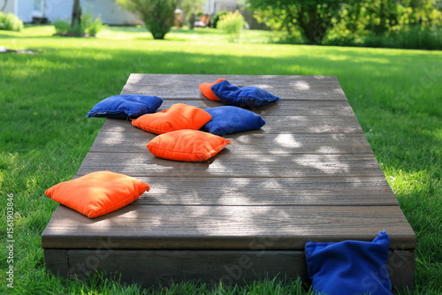 Blue and orange cornhole bags on a board during a backyard game